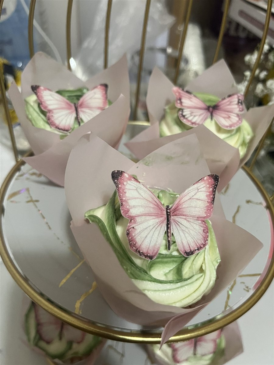 Green buttercream cupcakes decorated with pink butterflies